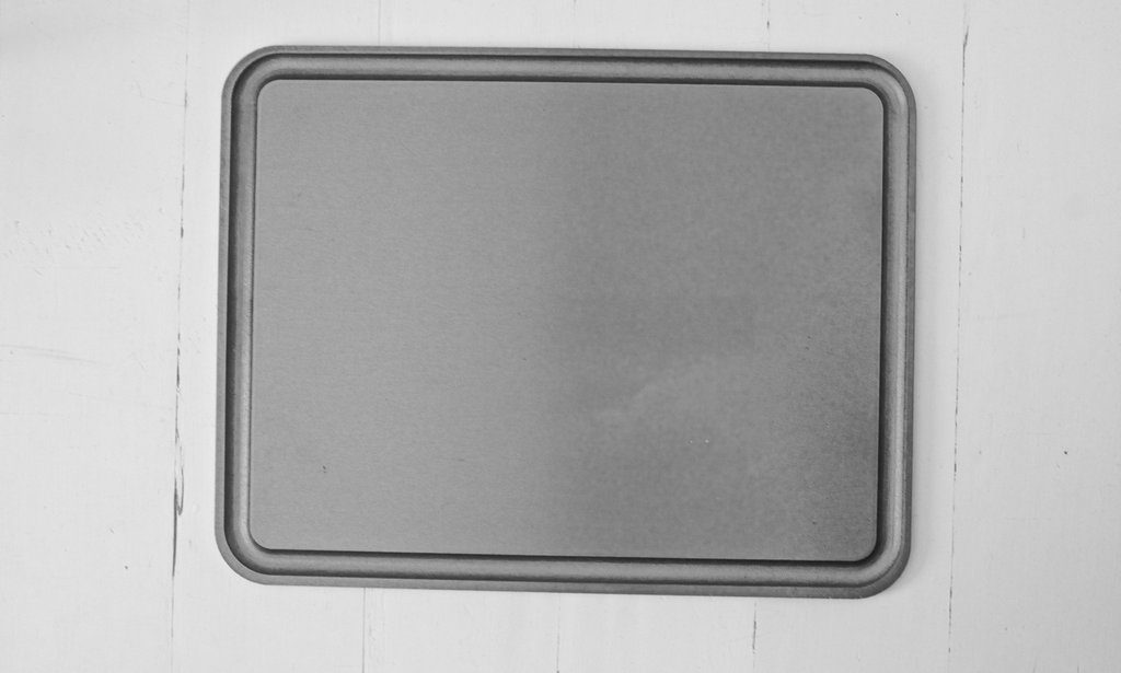 A Baking Steel reversible griddle accessory on a weathered white background.