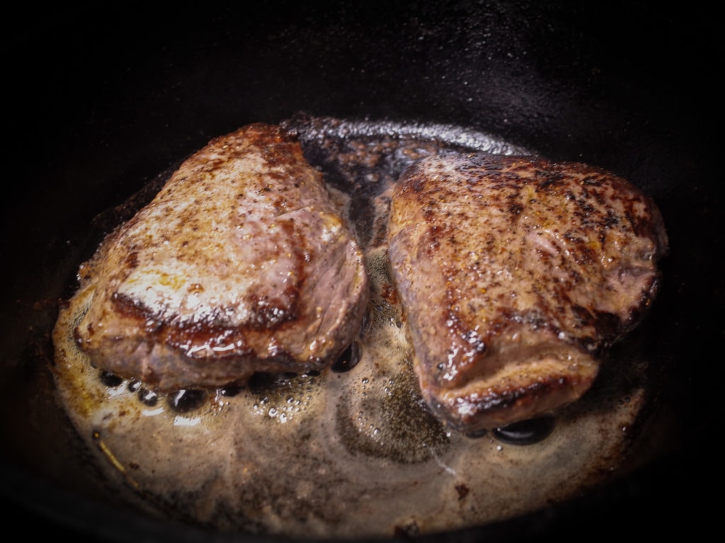 Two Koji rubbed sirloin steaks searing in cast iron.