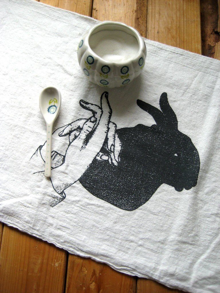 Organic cotton tea towel with black print of rabbit shadow puppet silhouette