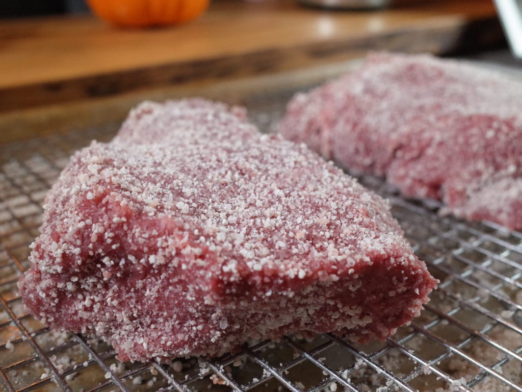 Two sirloin steaks on a rack rubbed with Koji Powder.