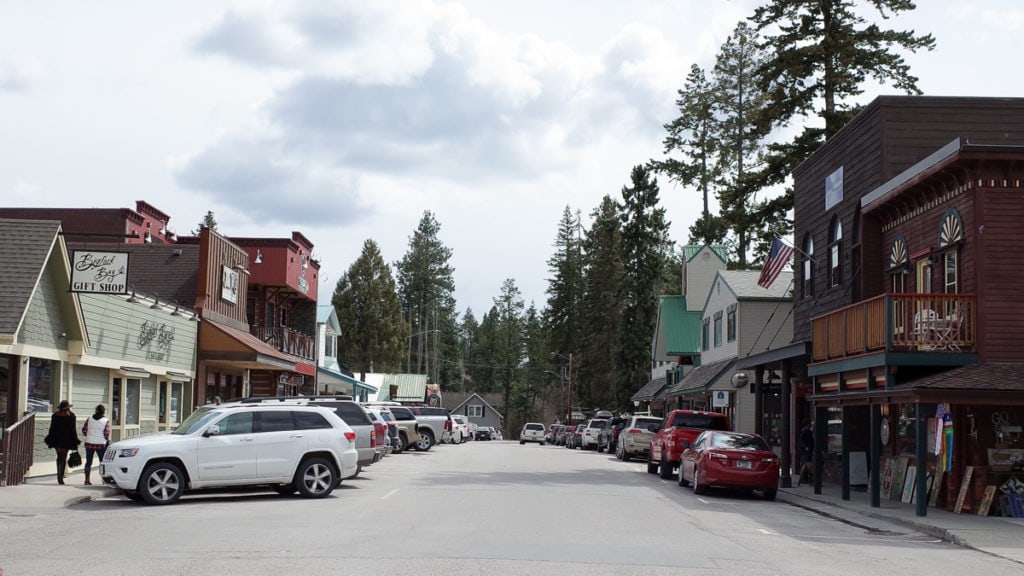 A view down Electric Ave. in downtown Whitefish, MT with cars parked on sides of road.