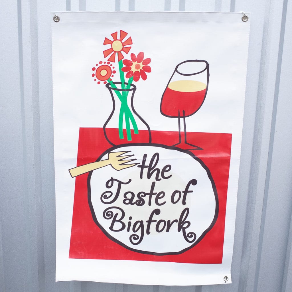 A Taste of Bigfork advertising banner against a galvanized steel wall.